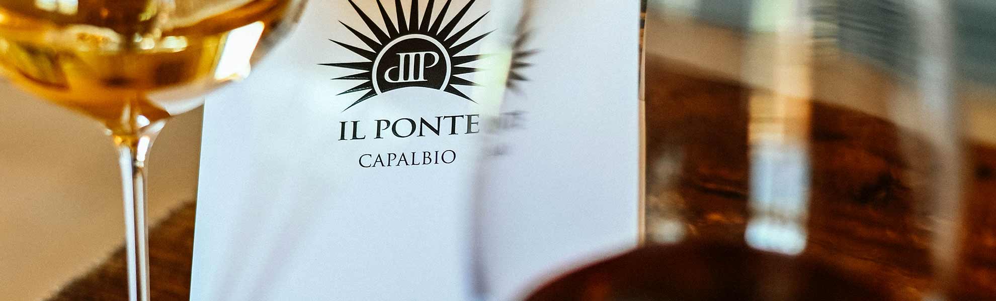 Dettaglio di una coppa di vino bianco appoggiata su una tavola di Agricola Il Ponte - Capalbio