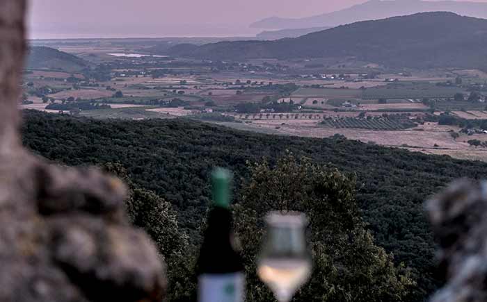 Una coppa di vino bianco ed l'affascinante paesaggio delle campagne di Capalbio.