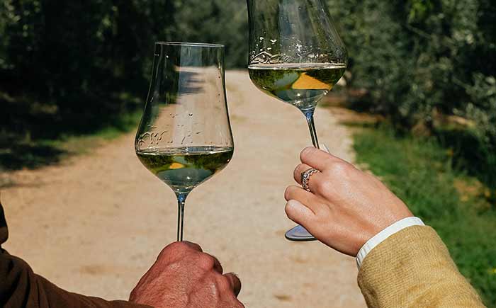 Un brindisi tra due coppe di vino bianco nella tenuta di Agricola Il Ponte a Capalbio.